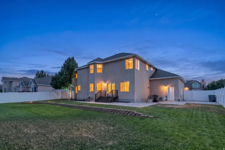 Spacious backyard with a manicured lawn, multi-level patio, and retaining wall