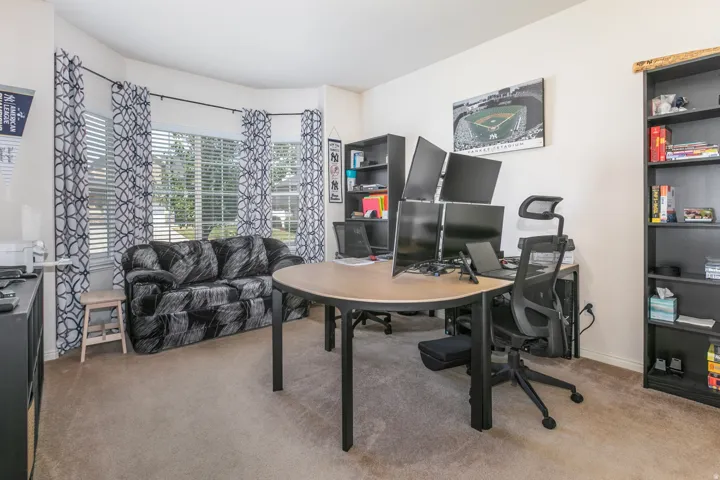 Spacious room featuring a bay window with blinds and patterned curtains