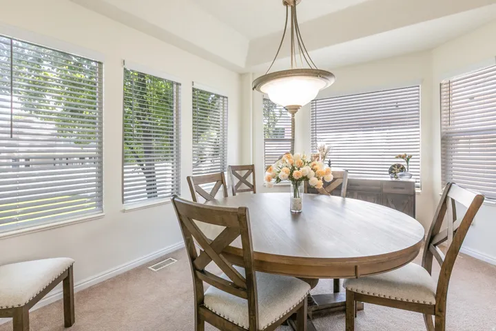 Dining area featuring a tray ceiling, multiple windows with blinds, and a built-in light fixture
