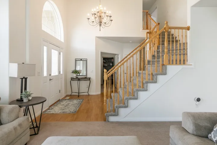 Two-story foyer featuring an arched transom window above double entry doors, wood-finish flooring, and a chandelier