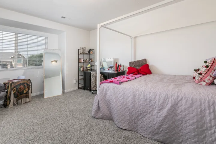 Carpeted room featuring a white-framed window with horizontal blinds, white walls, and white baseboards
