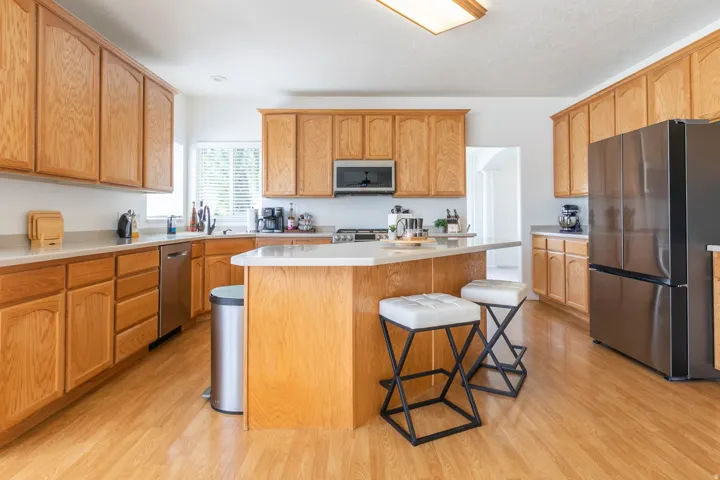 Open-concept kitchen featuring extensive light wood cabinetry, light-toned countertops, and wood-finish flooring