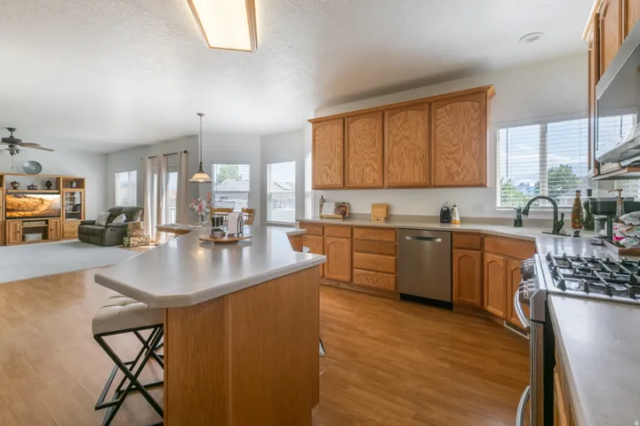 Open-concept kitchen featuring wood cabinetry, stainless steel appliances, and a central island with countertop seating