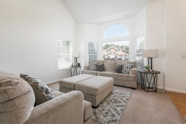Bay window with an arched transom, tall ceilings, and neutral carpeting