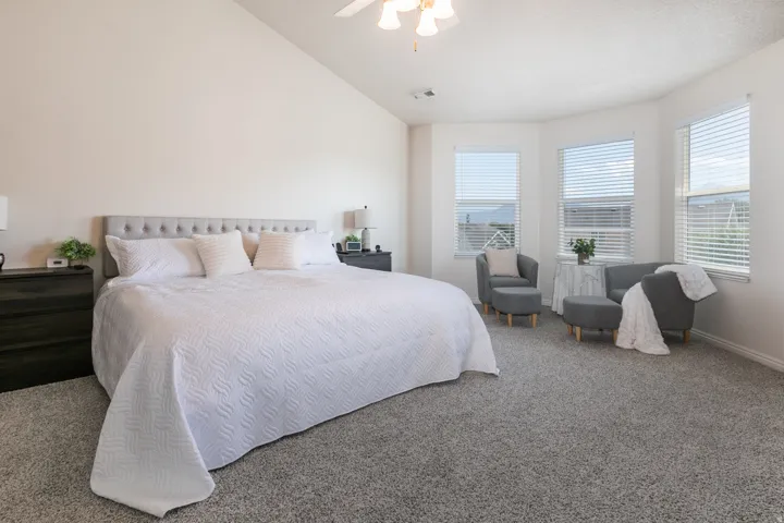 Spacious room featuring vaulted ceilings, a large bank of windows, and soft gray carpeting