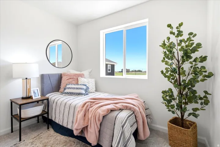 Neutral tone walls with a prominent window, carpeted flooring, and a built-in upholstered headboard