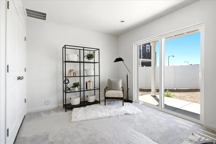 Carpeted room with white walls, featuring a sliding glass door to an outdoor patio area