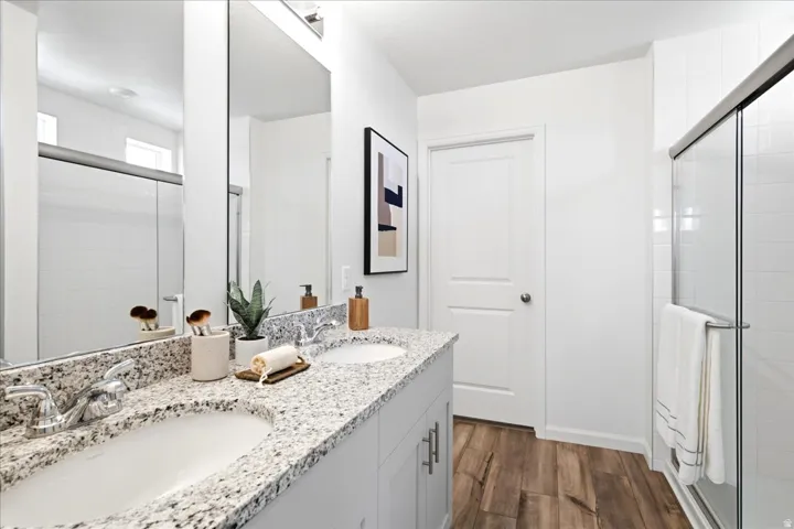 Bathroom featuring a dual vanity with light-toned countertops, two undermount sinks, and chrome faucets