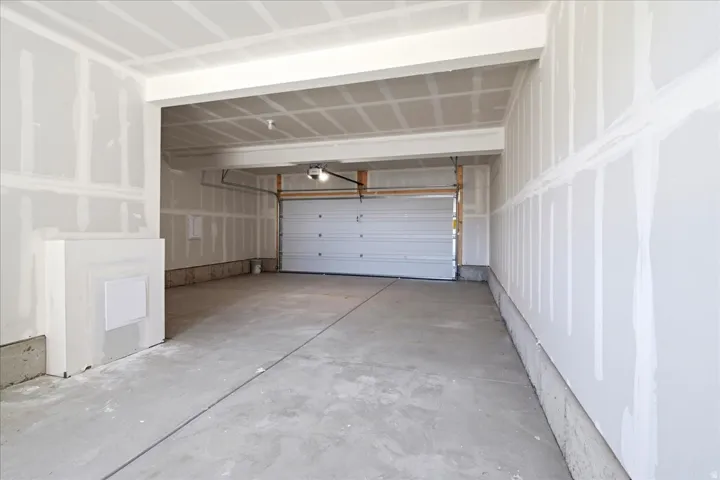Spacious garage featuring a concrete floor, an overhead door, and exposed drywall