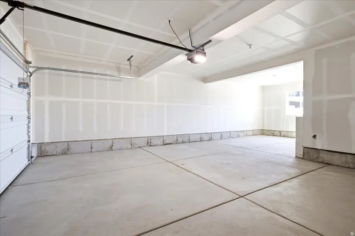 Spacious garage featuring a sectional garage door, concrete flooring, exposed drywall, and an overhead light fixture