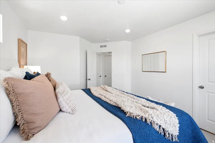 Bedroom featuring recessed lighting, a white painted door with brushed nickel hardware, and a framed wall mirror
