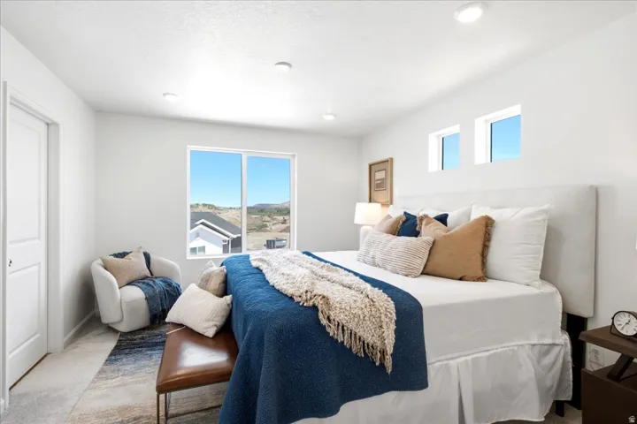 Bright interior space featuring a large window with distant hillside scenery, two high transom windows, recessed ceiling lighting, and a solid white door