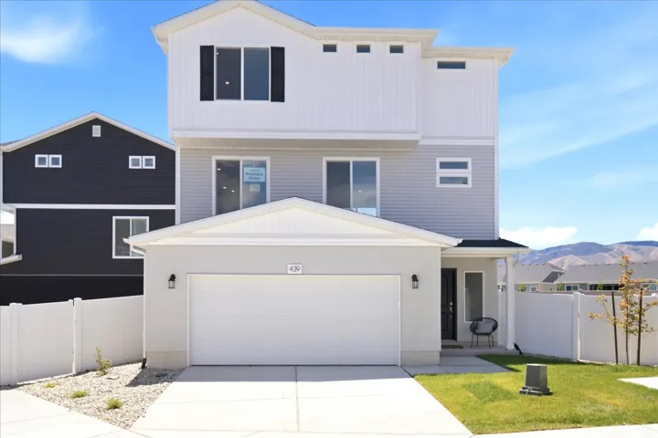 Modern three-story residence featuring a two-tone facade with white vertical siding and light gray horizontal siding
