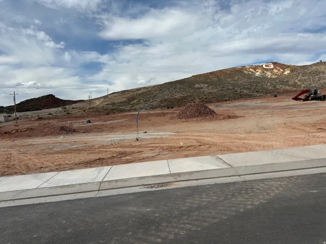 Cleared land parcel with a paved street, concrete curb, and sidewalk in place