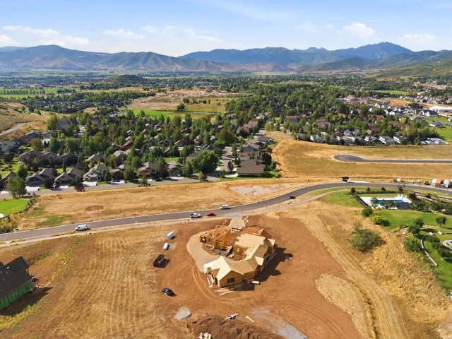 Expansive undeveloped lot featuring a partially constructed property, surrounded by natural terrain and distant mountains