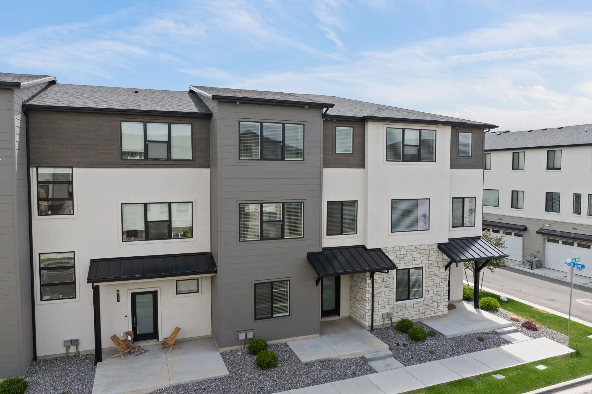 Contemporary townhome exterior featuring a multi-tone facade with white stucco, gray siding, and dark wood-finish accents