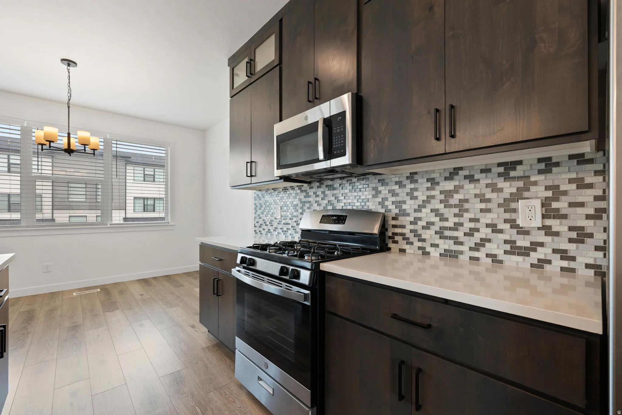 Modern kitchen featuring dark wood-finish cabinetry, stainless steel appliances, and light-toned countertops