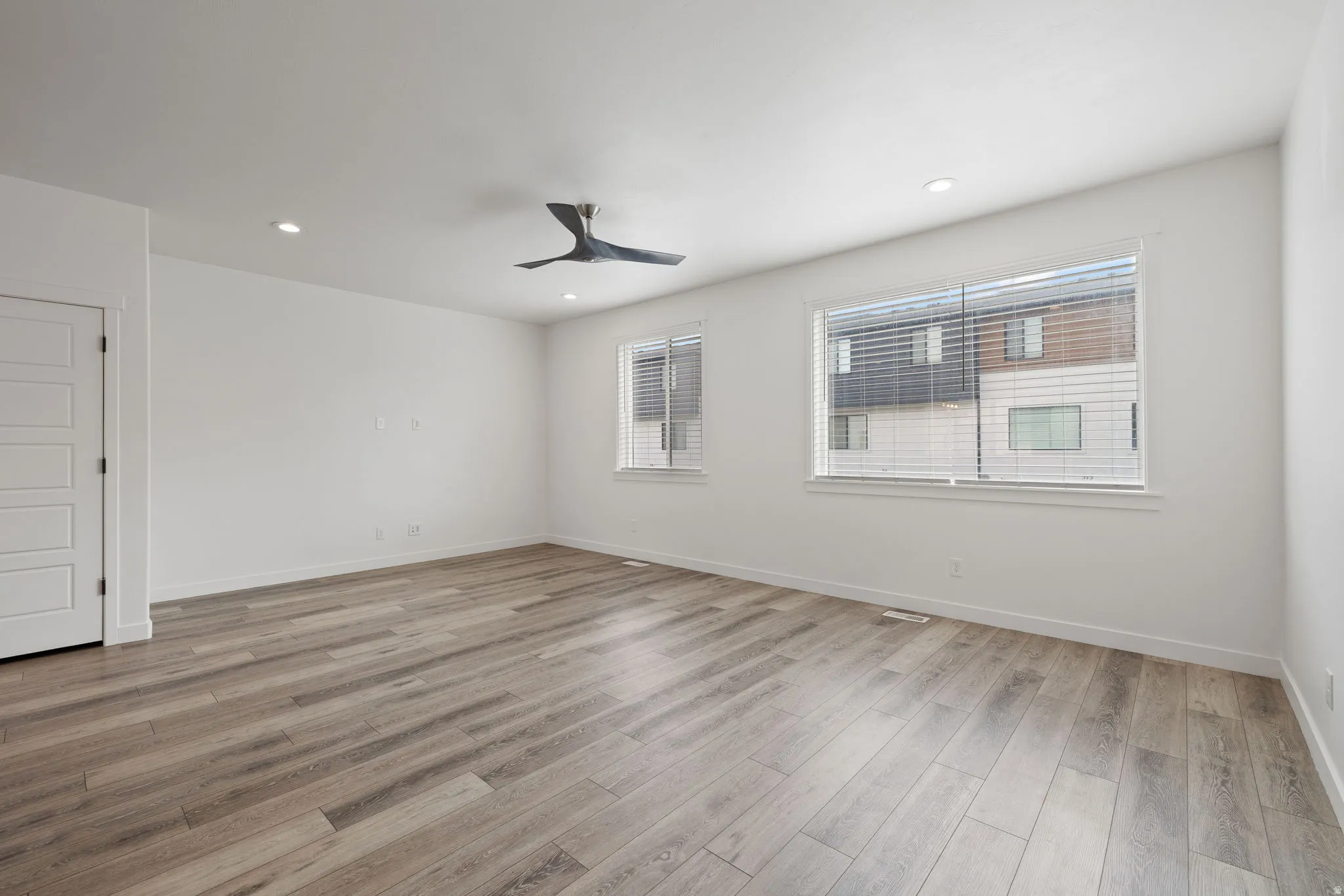 Spacious room featuring wood-finish flooring, recessed lighting, and a modern ceiling fan