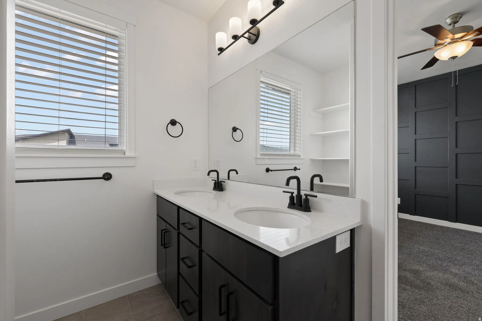 Dual sink vanity with white countertop, dark cabinetry, and matte black fixtures