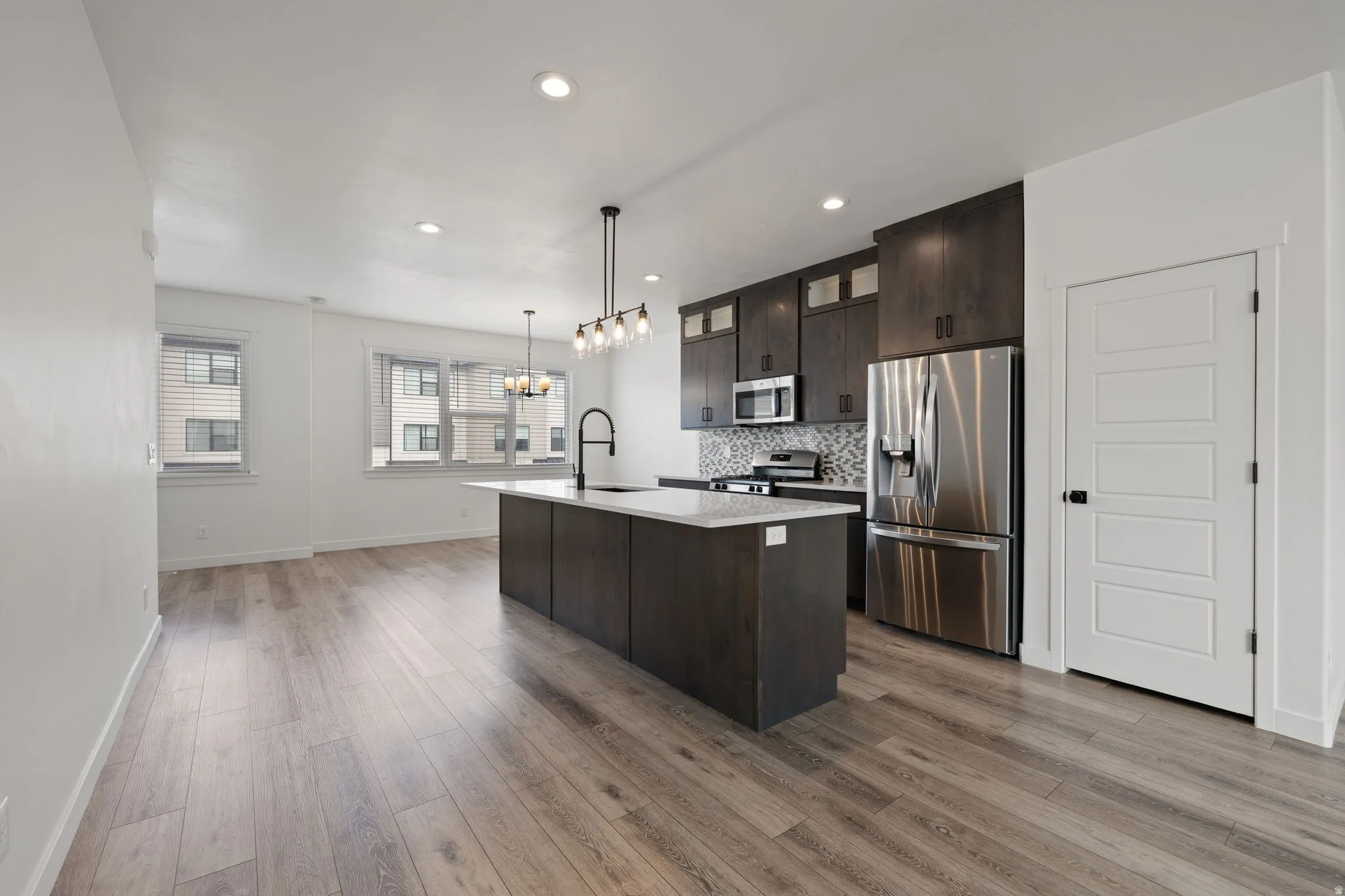 Modern kitchen featuring dark wood-finish cabinetry, stainless steel appliances, and a mosaic tile backsplash