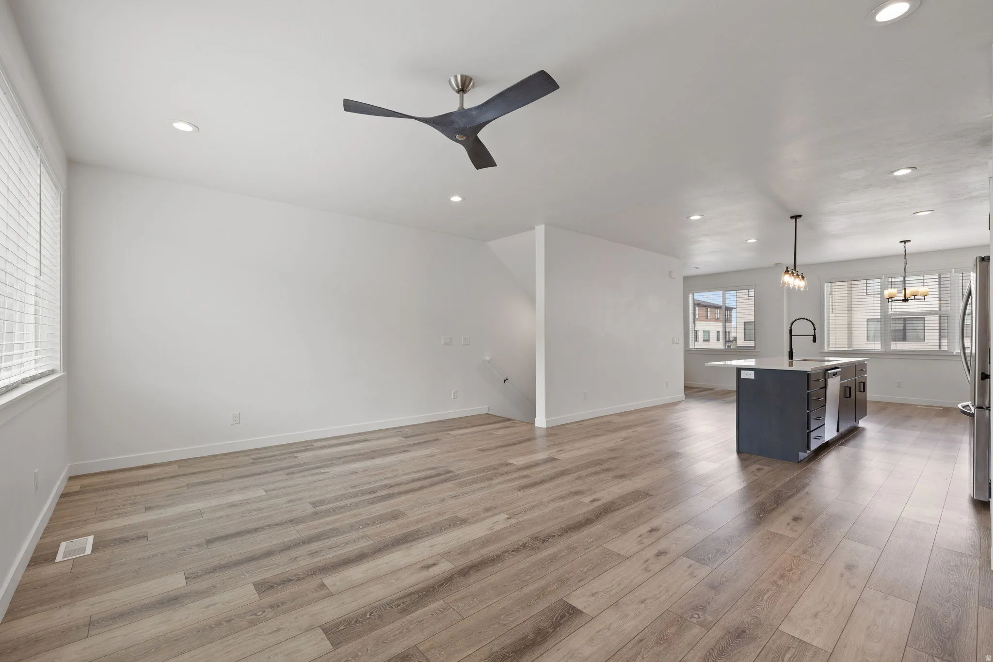 Open-concept living area featuring wood-finish flooring, recessed lighting, and a modern ceiling fan