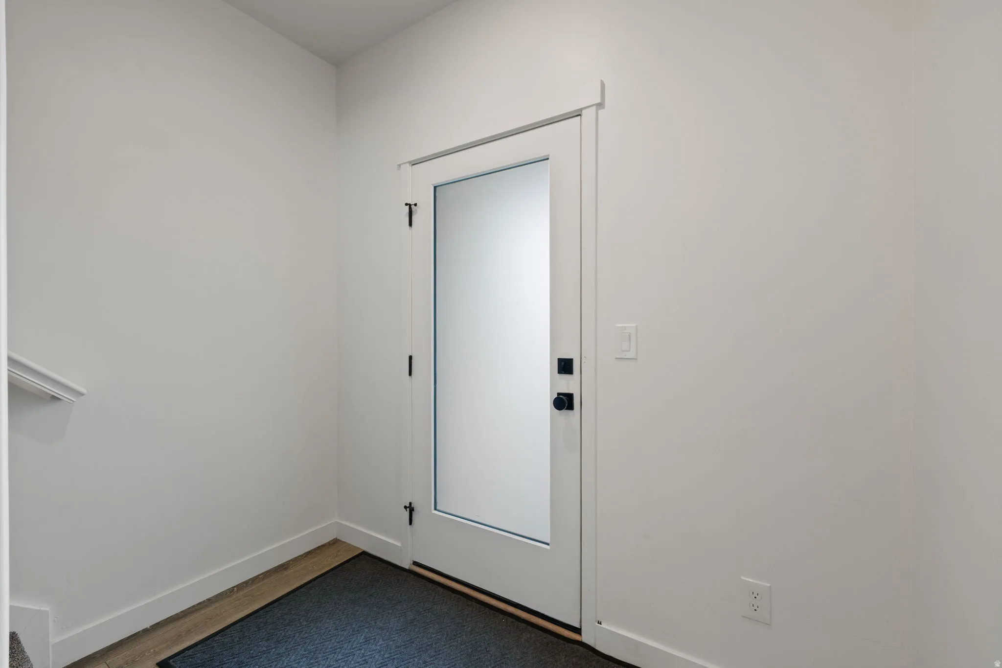 Entryway with a contemporary door featuring frosted glass and matte black hardware, framed by white trim