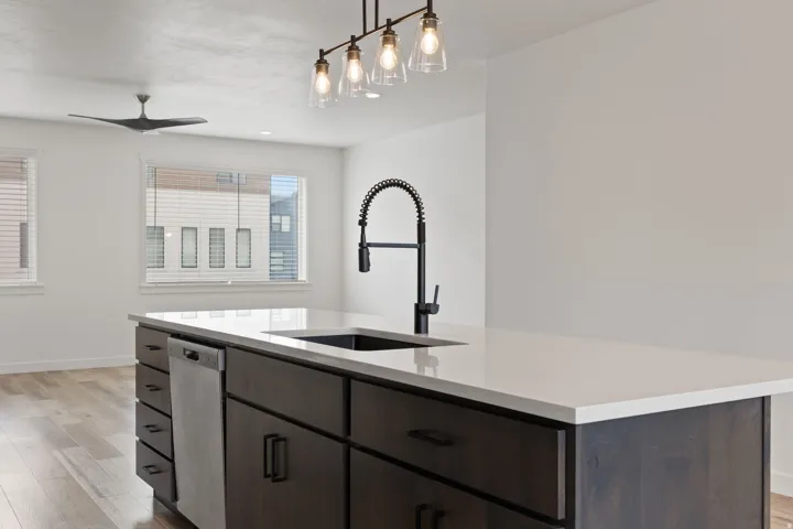 Kitchen island featuring a white countertop, dark wood-finish cabinetry, and a black gooseneck faucet with an integrated sprayer