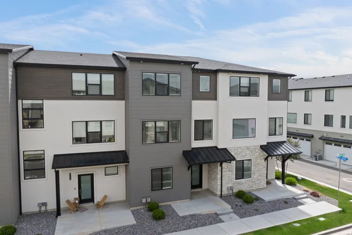 Contemporary townhome exterior featuring a multi-tone facade with white stucco, gray siding, and dark wood-finish accents