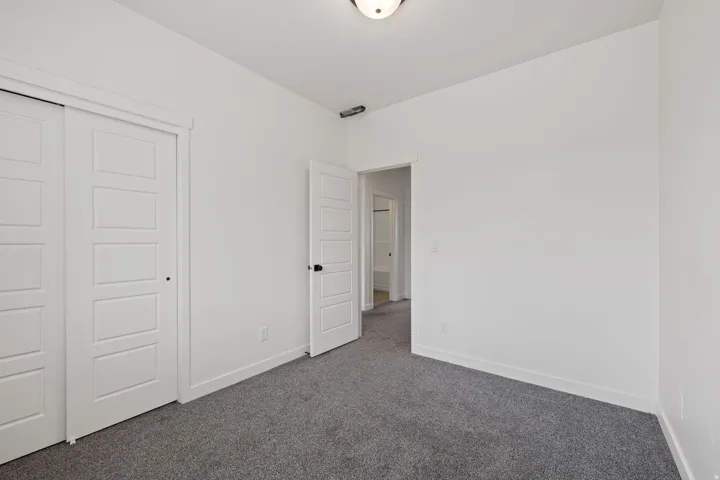 Neutral-toned room featuring a ceiling-mounted light fixture, gray carpet flooring, and white baseboards