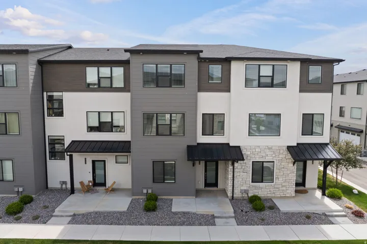 Contemporary multi-story facade featuring mixed-material siding, large windows, and dark-framed awnings
