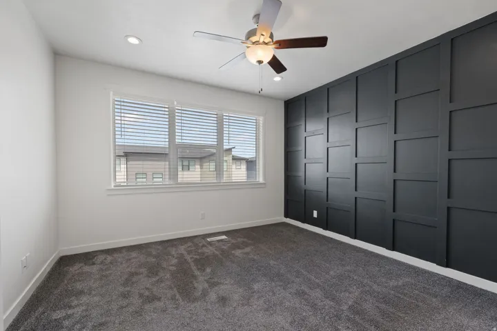 Room featuring a dark accent wall with geometric paneling, recessed lighting, and a ceiling fan