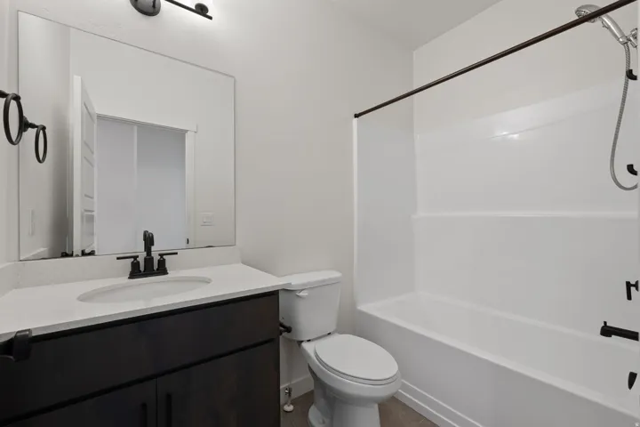 Bathroom featuring a dark wood-finish vanity with a light countertop and undermount sink, matte black faucet hardware, and a framed mirror