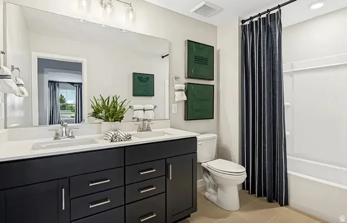 Bathroom featuring a double vanity with dark cabinetry, white countertops, dual undermount sinks, and polished chrome fixtures
