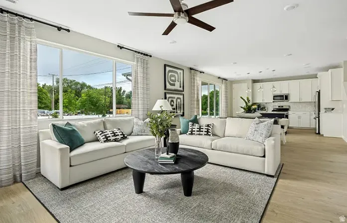 Open-concept living area featuring light wood-finish flooring, recessed lighting, and a dark wood-blade ceiling fan