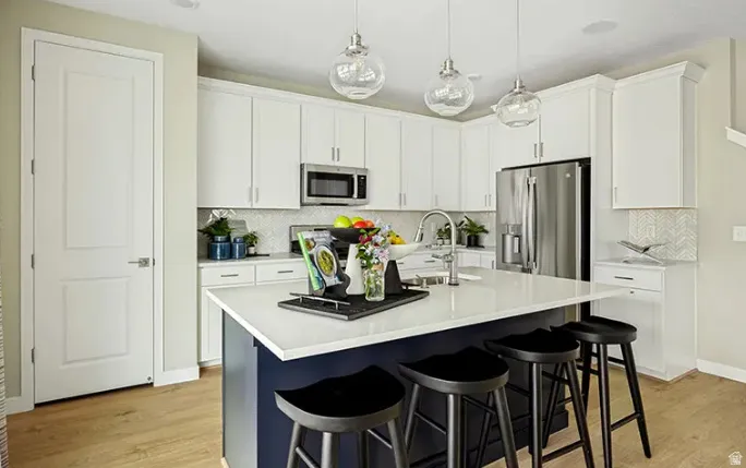 Kitchen featuring a central island with a solid surface countertop, white cabinetry, stainless steel appliances, and wood-finish flooring