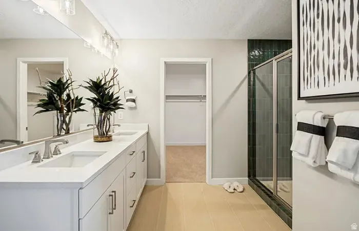 Double vanity with white cabinetry and integrated sinks, complemented by a full-width mirror and polished chrome light fixtures