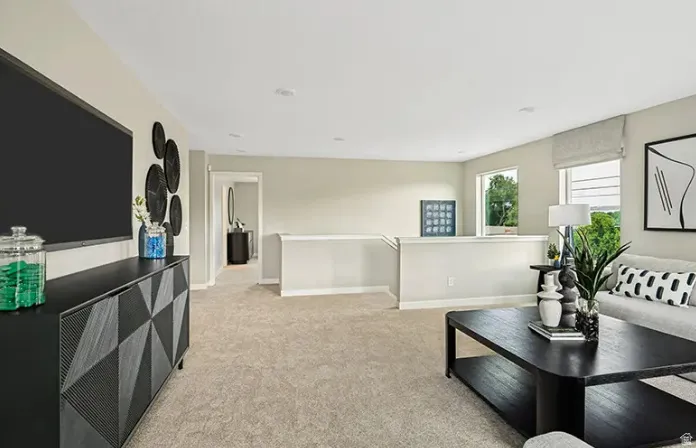 Open loft area featuring neutral-toned carpeting, recessed lighting, and ample natural light from multiple windows