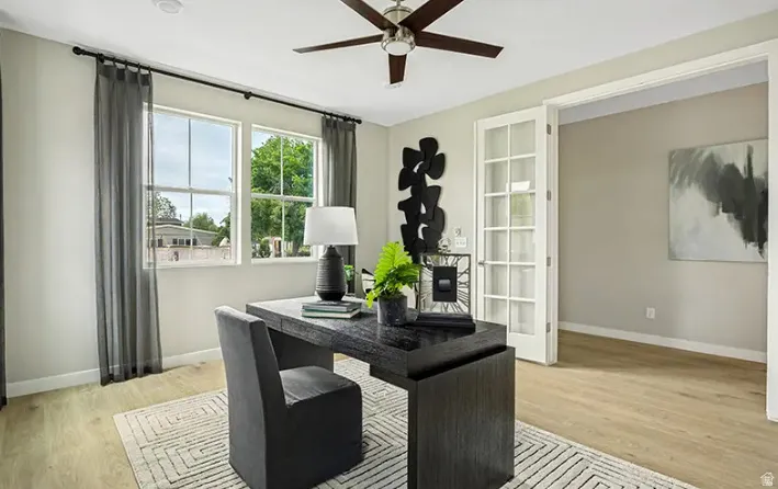 Bright room featuring wood-finish flooring, a ceiling fan with integrated lighting, and two large windows