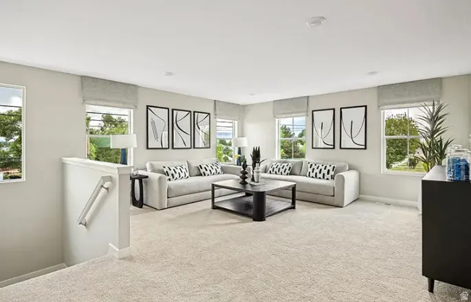 Spacious carpeted room featuring multiple windows, a white baluster railing, recessed lighting, and light-toned walls