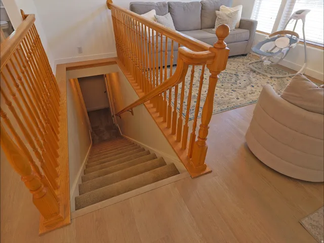 Staircase with light wood newel posts and spindles, carpeted treads, and wood-finish flooring at the landing