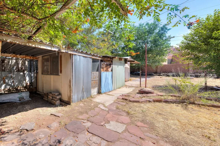 Backyard featuring a shed with corrugated metal siding, an exposed beam pergola, and a stone paver path