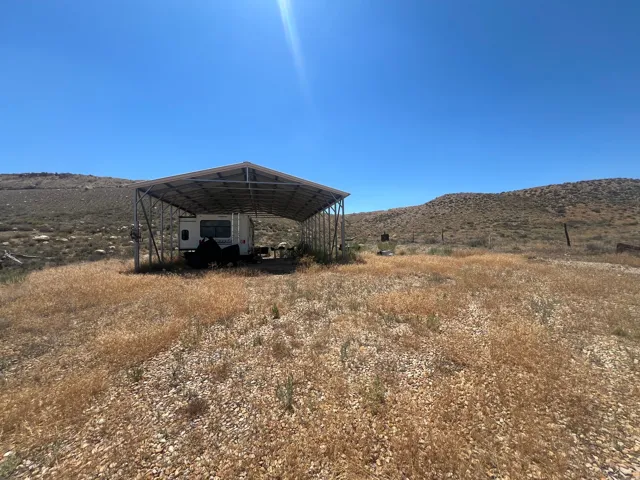 Expansive open land featuring a metal-framed carport structure