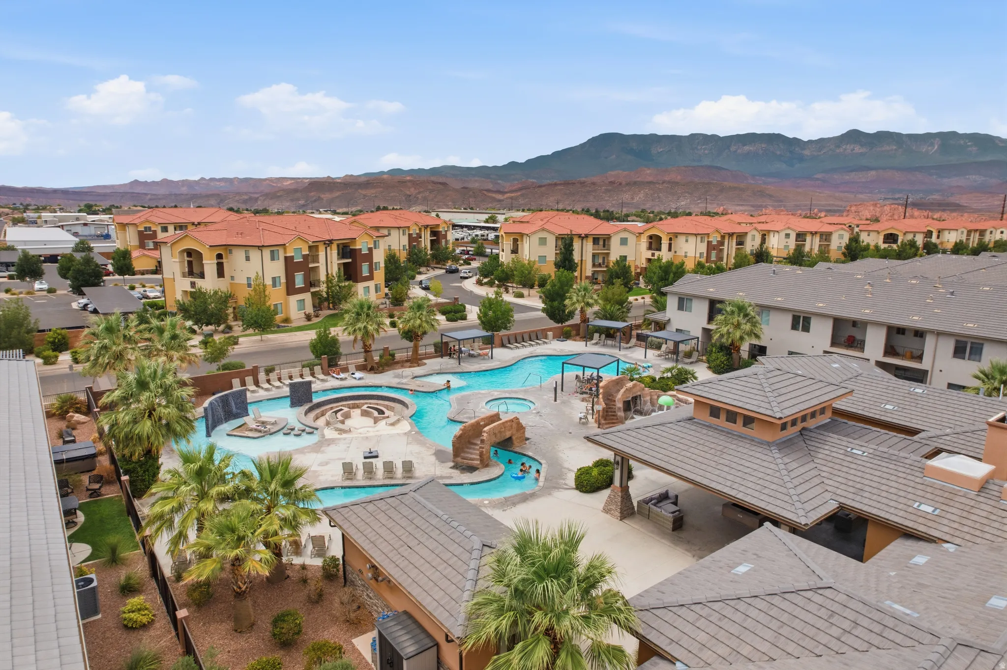 Resort-style pool area featuring multiple swimming zones, a circular spa, and an integrated water feature
