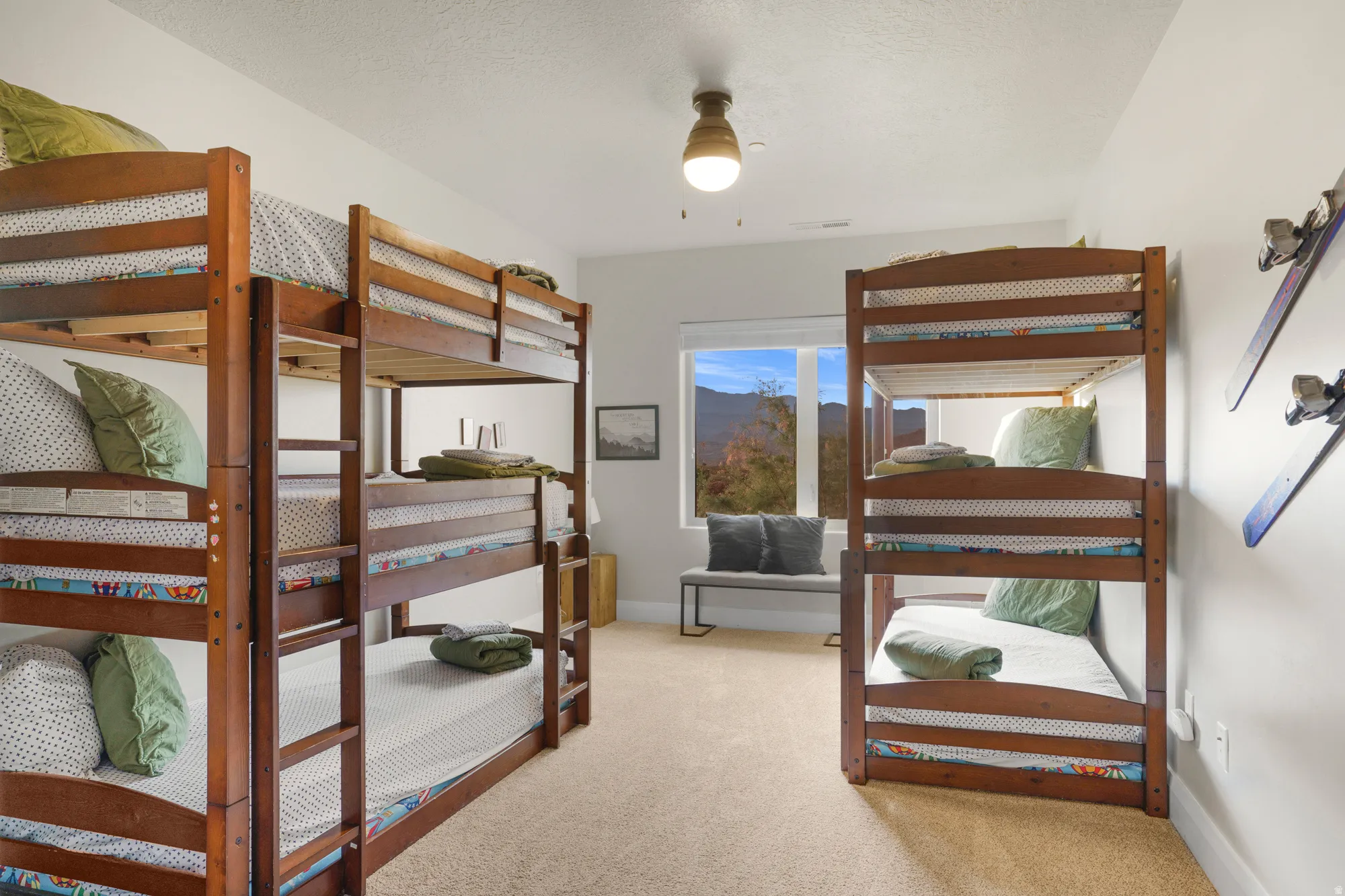 Carpeted room featuring multiple wood bunk beds, a large window with mountain scenery, and a ceiling-mounted light fixture