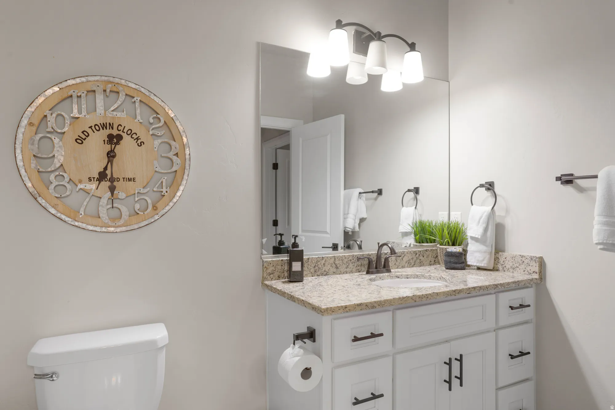 Bathroom featuring a light-colored vanity with a granite countertop and an undermount sink