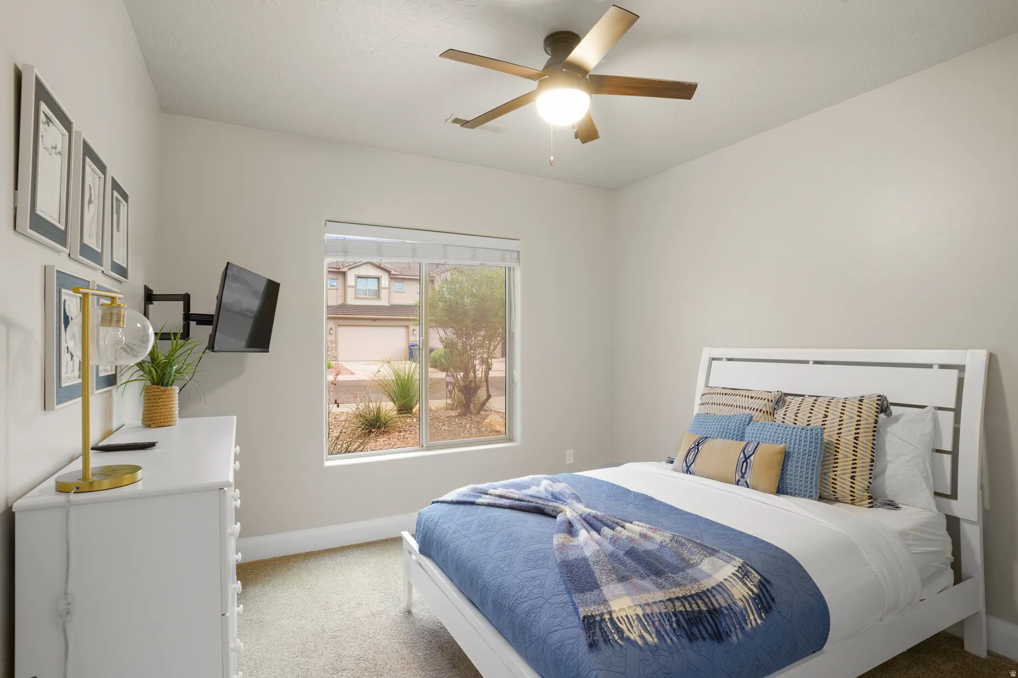 Recessed window with blinds, ceiling fan with integrated lighting, wall-mounted television bracket, neutral wall paint, and carpeted flooring