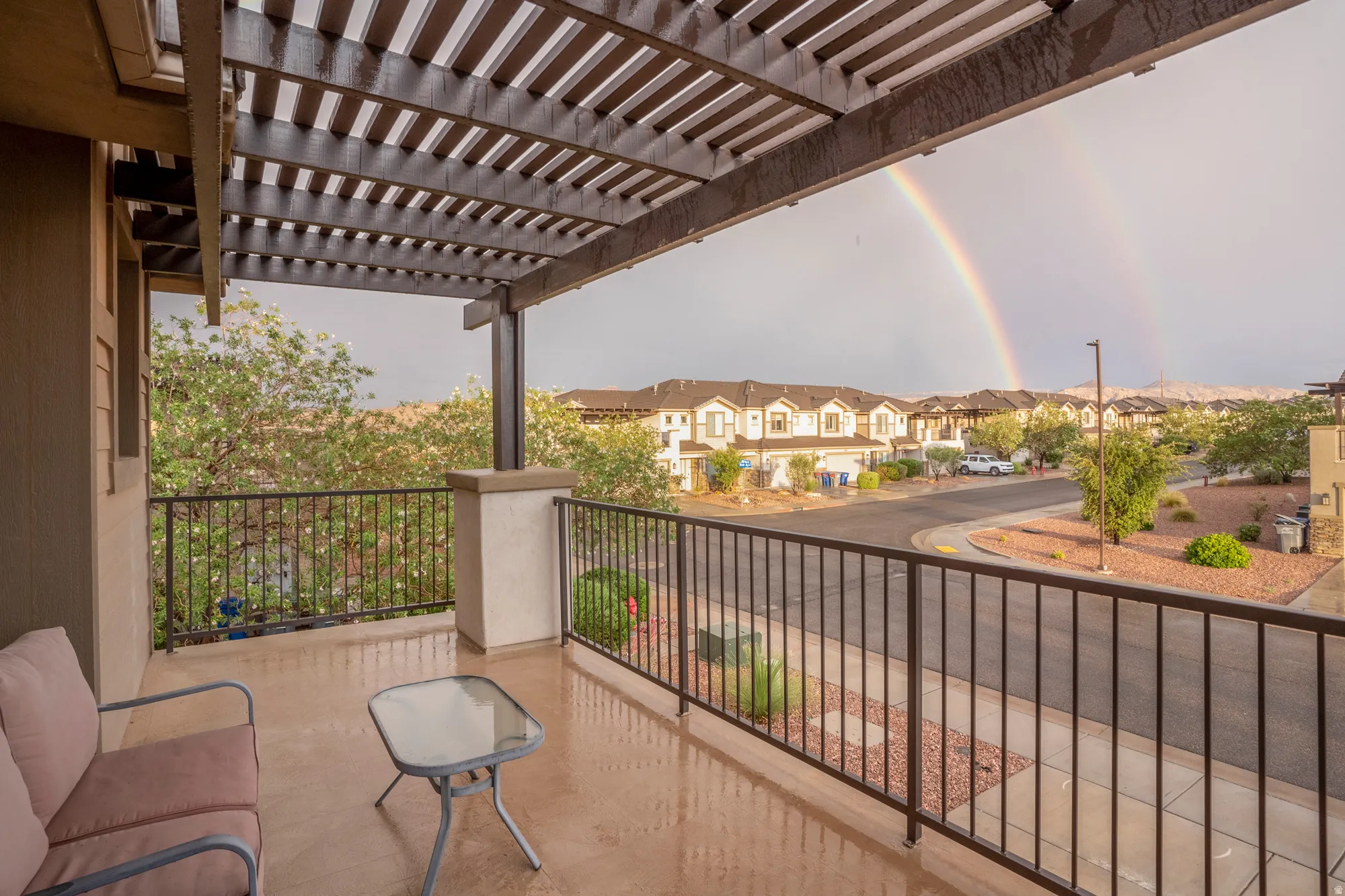 Covered balcony featuring a wood-slat pergola, concrete flooring, and black metal railings