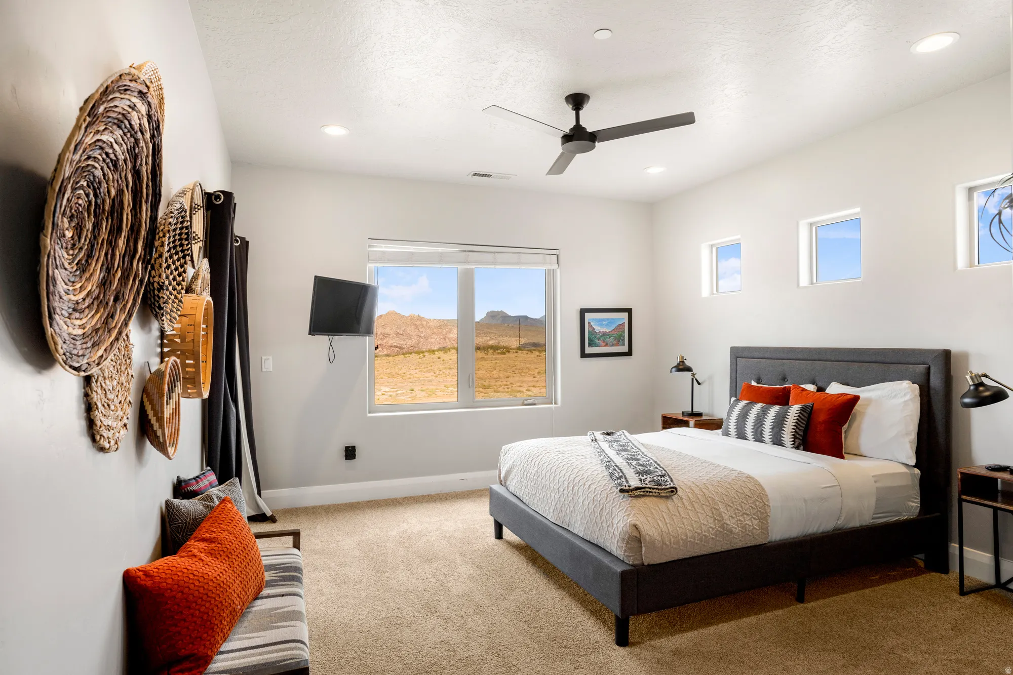 Carpeted bedroom featuring a large window with desert scenery, recessed lighting, a ceiling fan, and multiple high windows