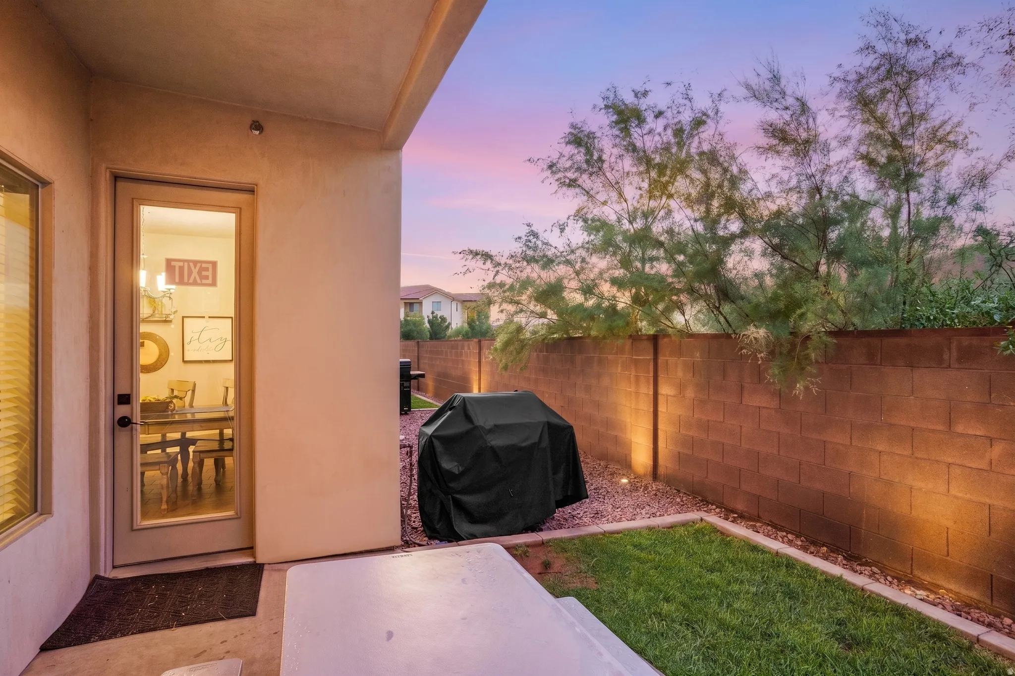 Covered patio area featuring a concrete slab, a small grass patch, and a gravel bed