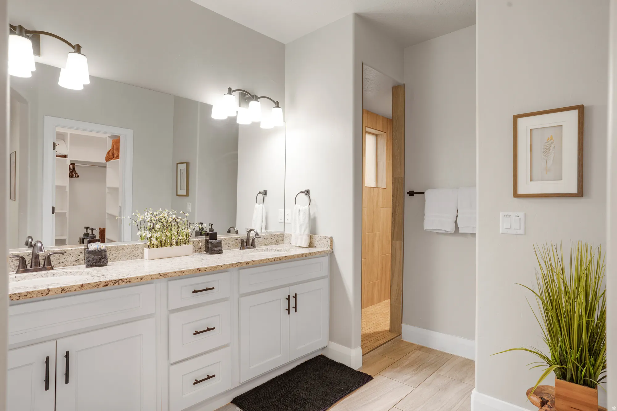 Dual vanity featuring white shaker cabinetry, dark hardware, and a light-toned speckled countertop